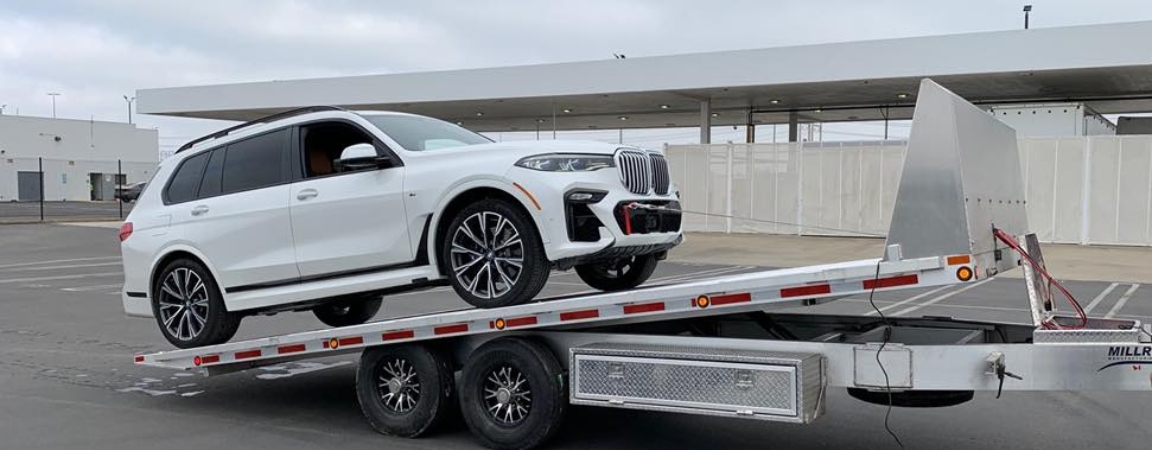 A white SUV being loaded onto a tilt trailer in a parking area, demonstrating the ease of vehicle transport with the tilting mechanism.